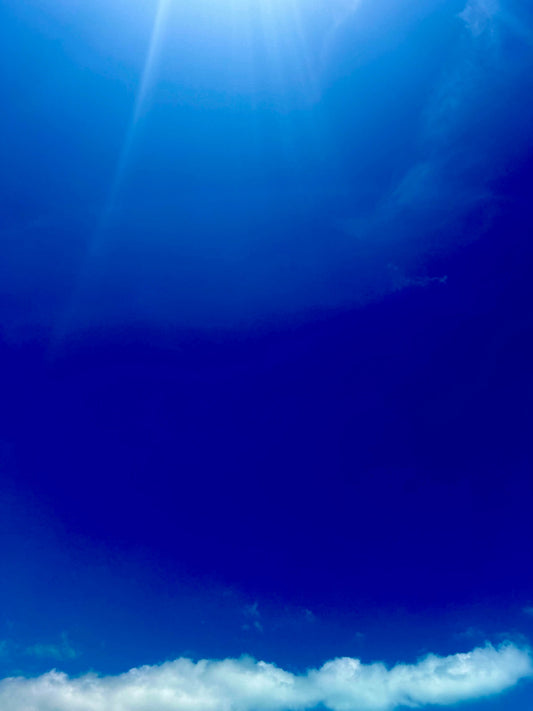 deep blue sky with sun beaming through clouds