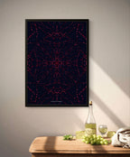 Framed abstract art piece with a geometric pattern on a wall above a wooden table with wine and grapes.